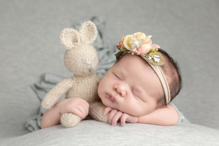 Newborn baby holding a cute bunny photographed by professional with elegant backdrop for girl in Orlando, Florida