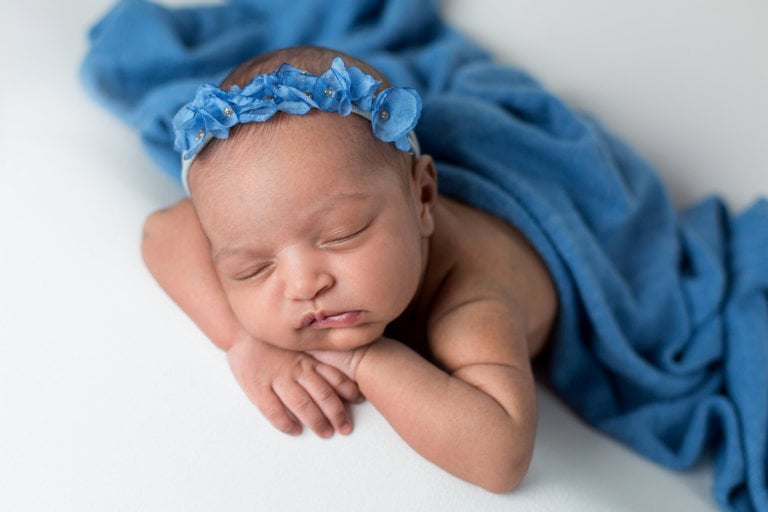 Newborn girl on ivory fabric blue wrap and blue headband closeup for girl in Scottsdale, AZ