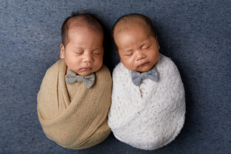 newborn baby twin boys swaddled in professional photography session with bow ties for multiples in 